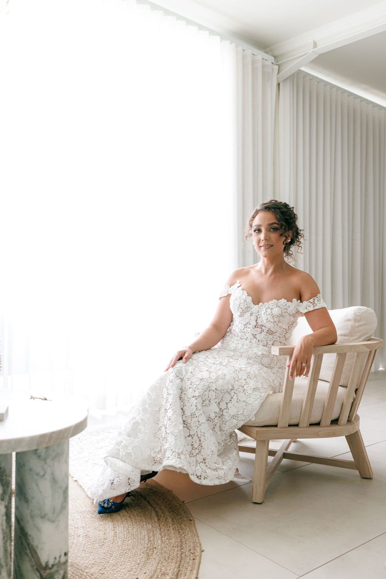 A bride seated in a light-filled white suite at STAY